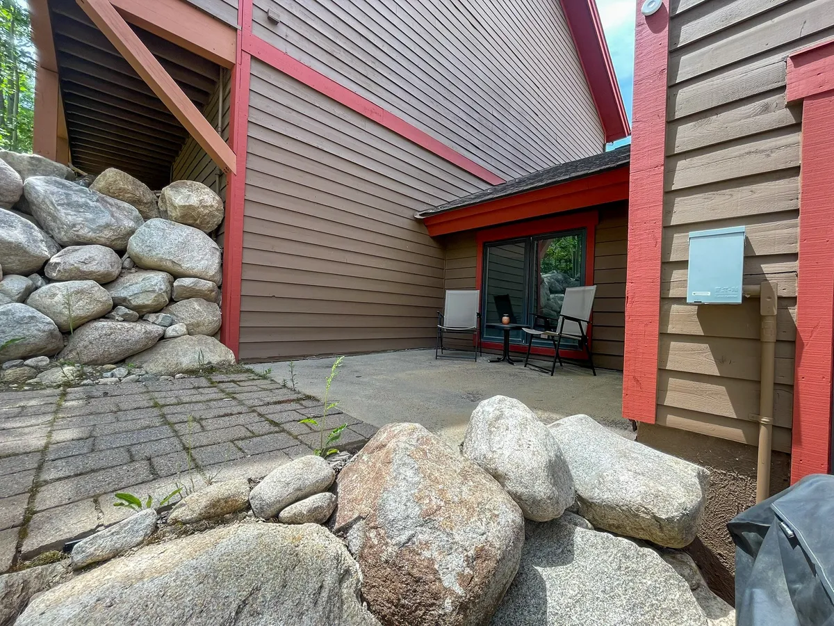A tranquil private patio just outside a sliding glass door, framed by natural rock formations and patio chairs—an ideal spot for relaxation and enjoying the outdoors.