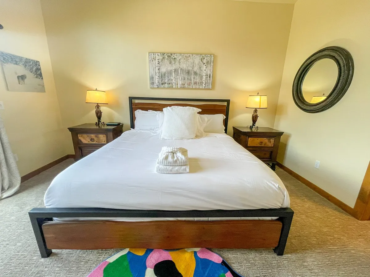 A tranquil bedroom with a neatly made bed, nightstands, a lamp, and soothing artwork. The room is bathed in soft natural light, creating a calm and restful retreat.