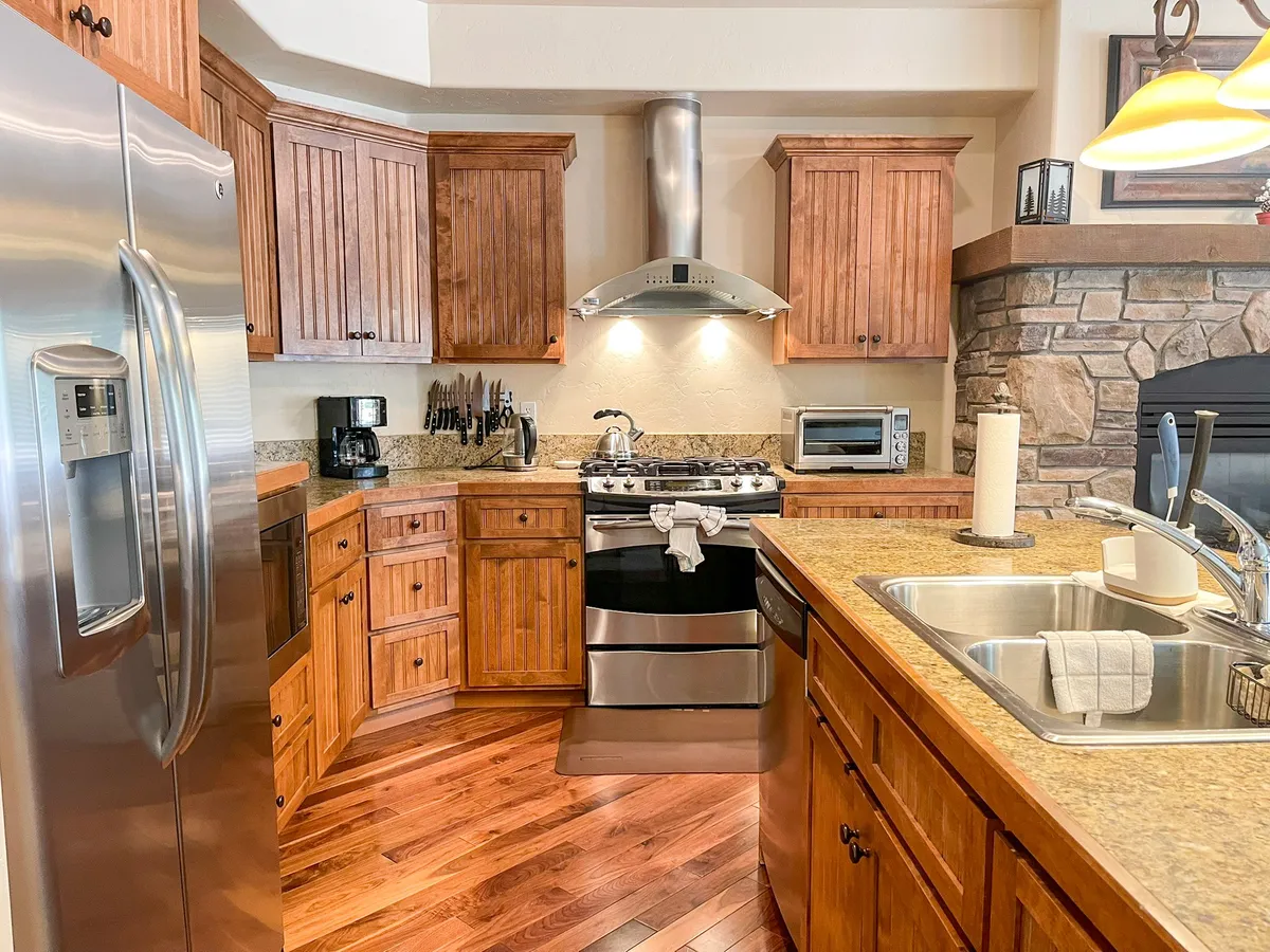 A spacious, modern kitchen with a central island, stainless steel appliances, wooden cabinetry, and granite countertops. The scene suggests a space ideal for cooking, baking, and gathering with loved ones, reinforcing the villa's gourmet kitchen amenities.